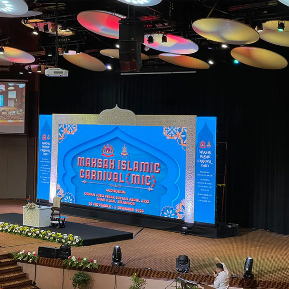 Conference stage with a wide LED screen and overhead scenic elements